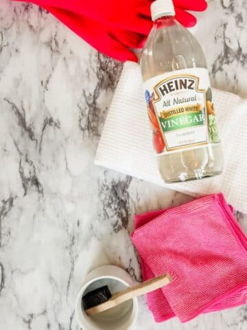 vinegar with cleaning supplies on a countertop