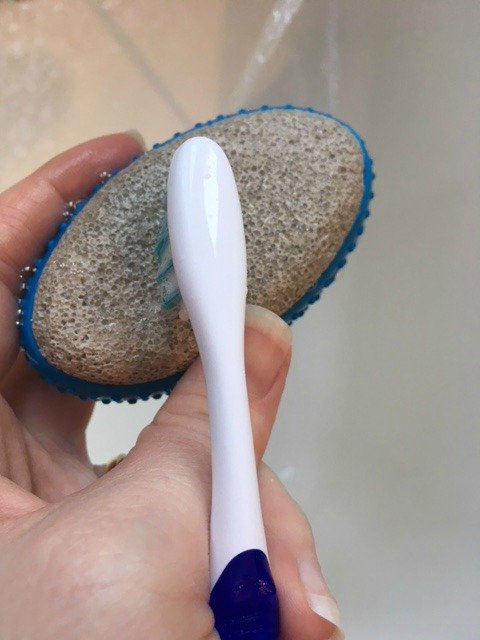 scrubbing a pumice stone clean using an old toothbrush.