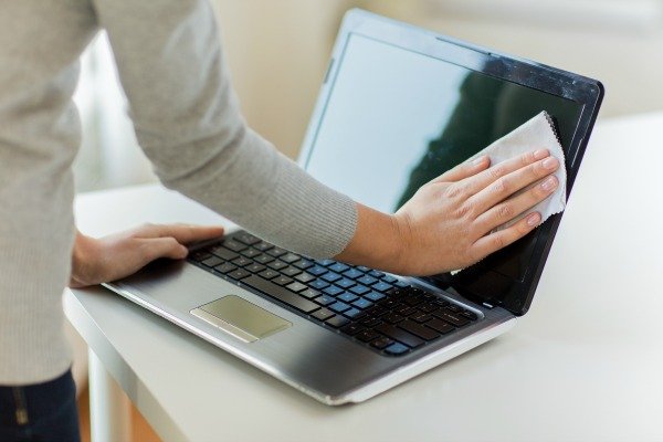 person cleaning laptop screen