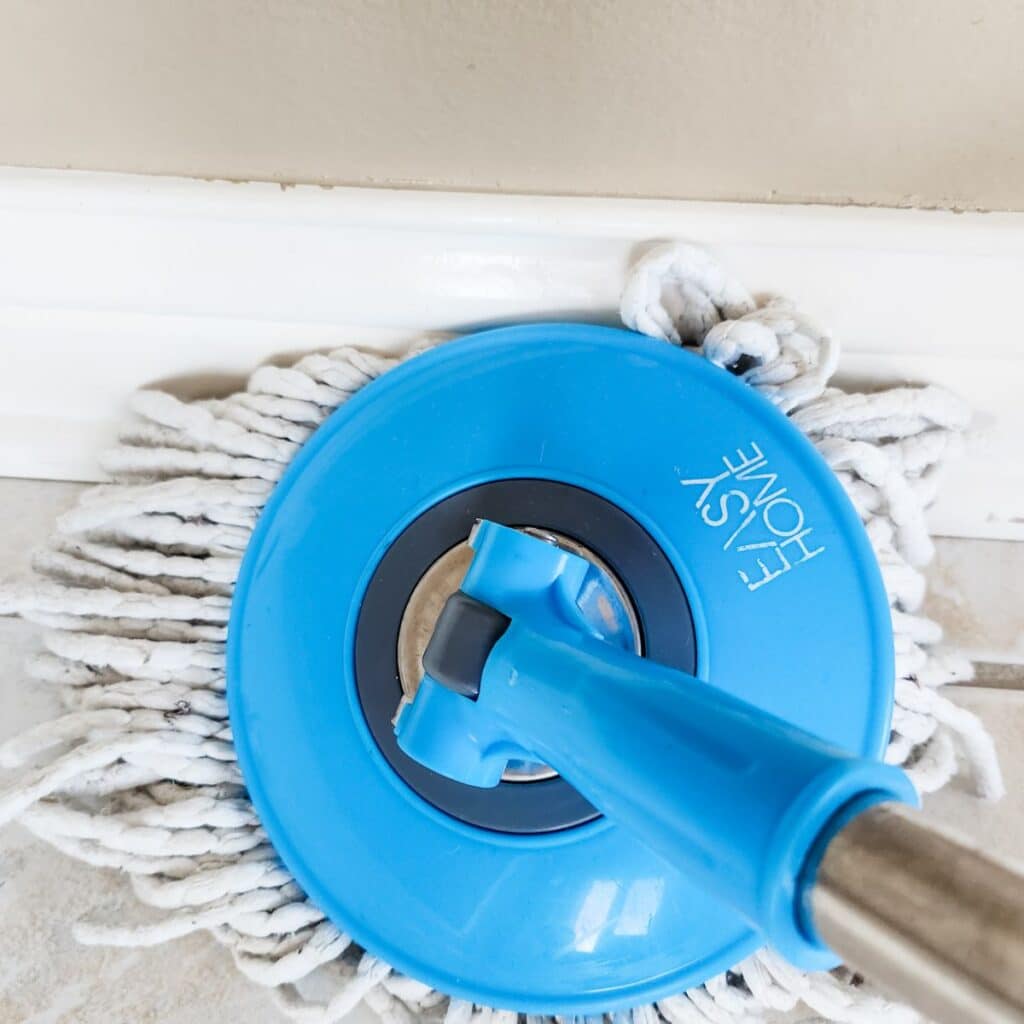 using a spin mop to clean baseboards.